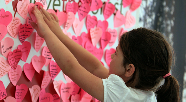 Girl sticks note to lovetheforest heart wall at the New Forest Show
