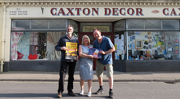 £1,000 FOR THE COMMUNITY L-R Steve Moody, Caxton Décor with Janine Pulford, Director mags4dorset and winner Mike Womersley receiving his cheque