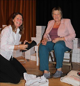 Sue Warr from POPP gives a pair of slippers to a visitor