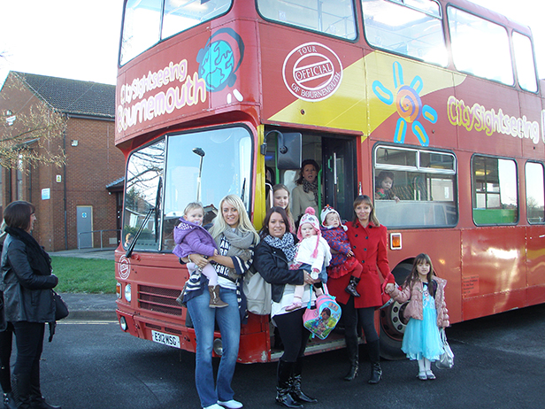 Parents and toddlers standing in front of panto bus