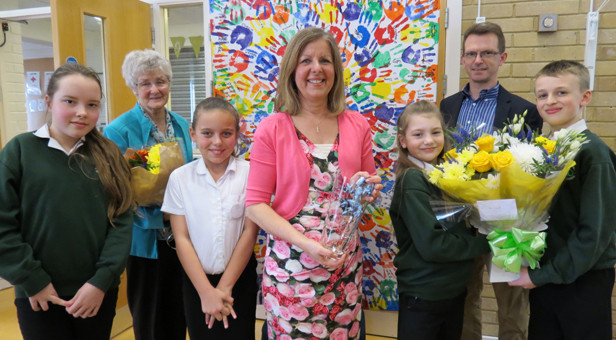 Schools out for Mrs Gould (centre) with gifts of an engraved vase from the school, flowers held by Brendon and Sienna, a photo canvas held by her husband Quartus and her mother Mary Woods, featuring the hand prints of all of the school’s 187 children including Alissa (far left) and Mia (left).
