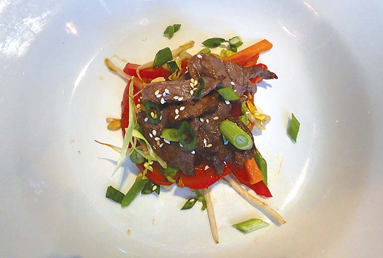 Asian beef salad with strips of beef marinated in soy, served with peanuts, chilli bok choi and beansprouts