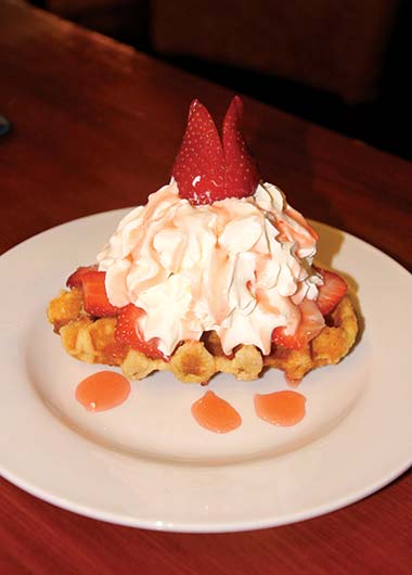 Belgian waffle with ice cream, strawberries and strawberry sauce