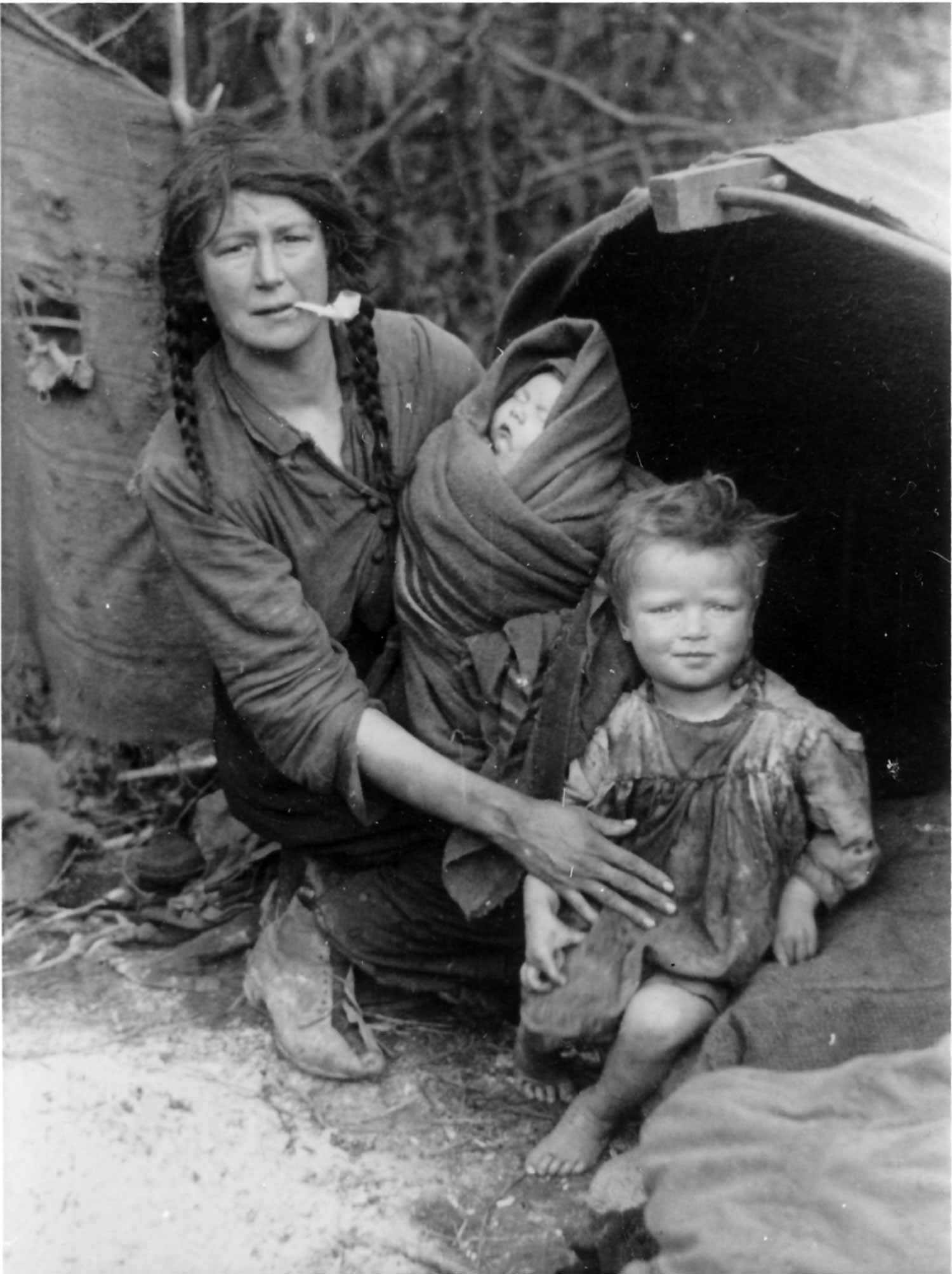 A Traveller woman smoking a clay pipe with her two children in the 1910s © Dorset History Centre