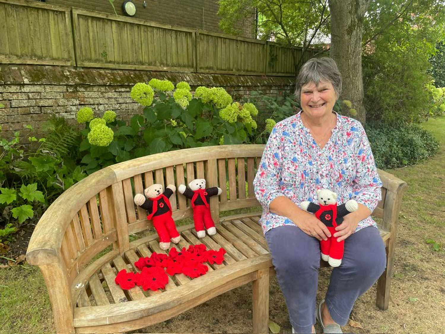 Museum volunteer Sally Palmer with some of the knitted poppies and Remembrance Teddies.